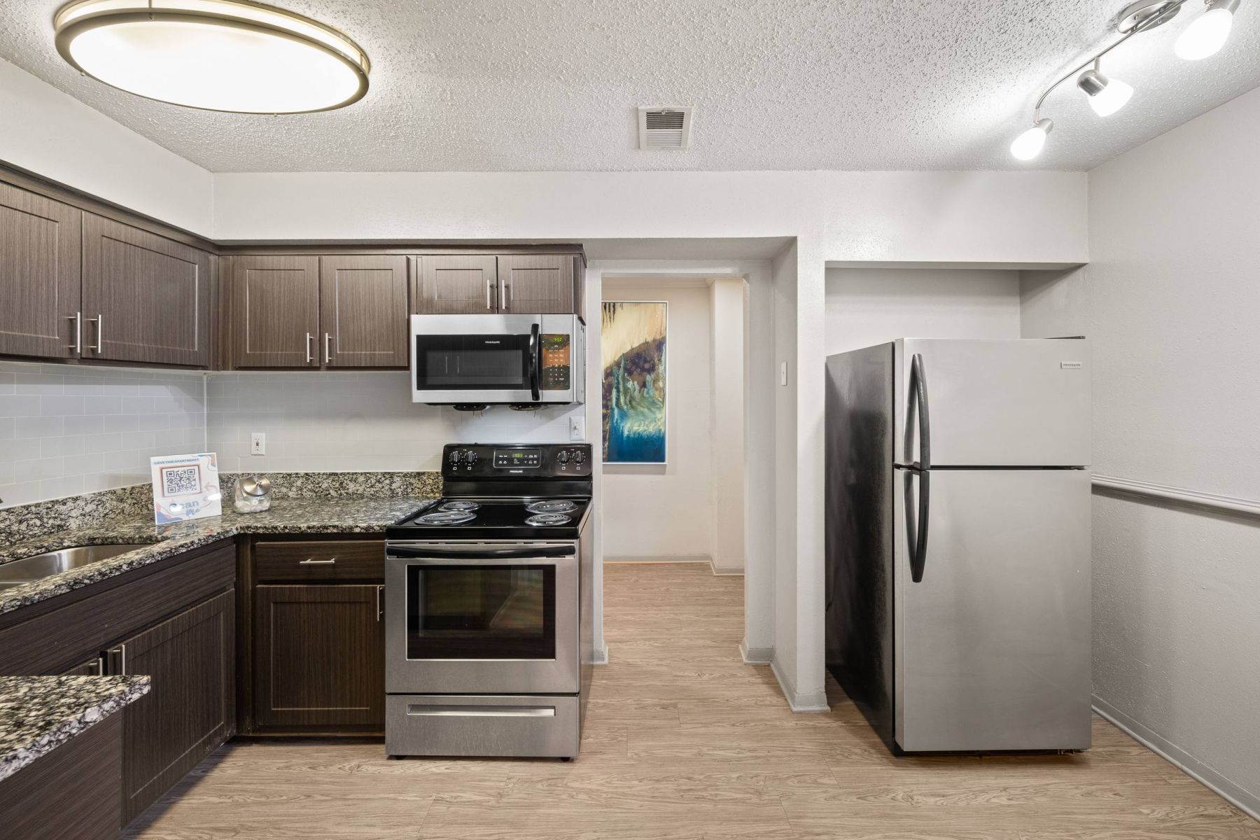 Empty room with wood floors, ceiling fan, and sliding glass door leading to a patio with vertical blinds at Apex West Midown.